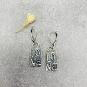 A pair of earrings with the word love on them.